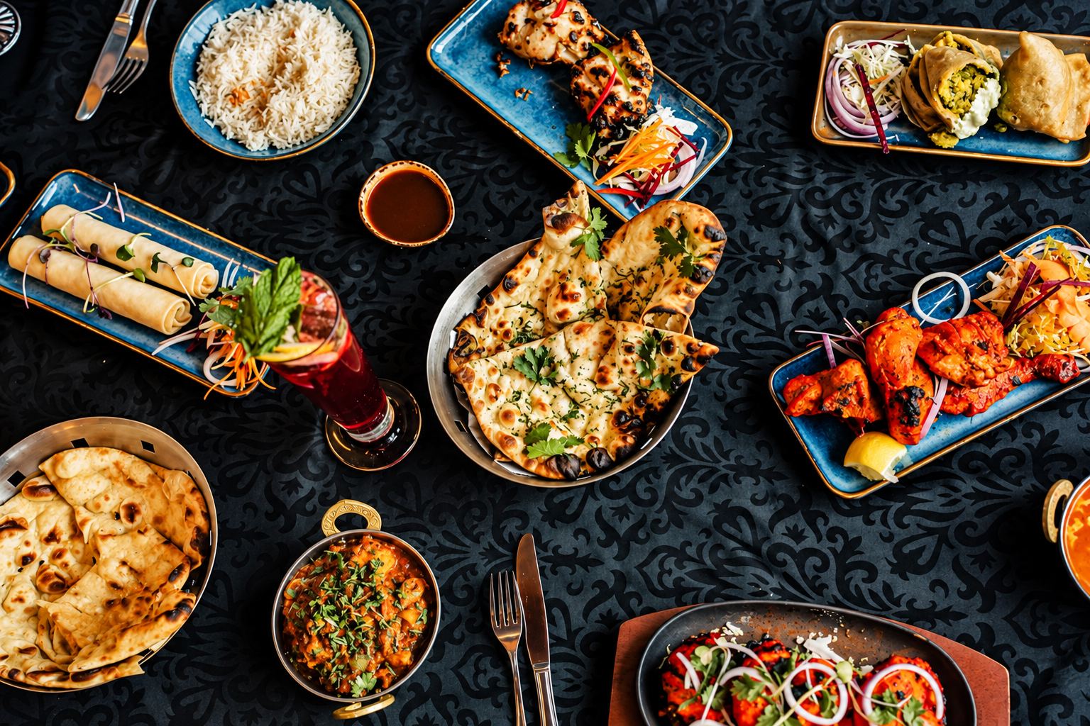 A table spread with curries, naan, tandoori dishes and drinks at Indian Dreams Rolleston